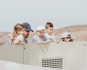 three children lean over the side of the heli-hydrant tank to see what is inside