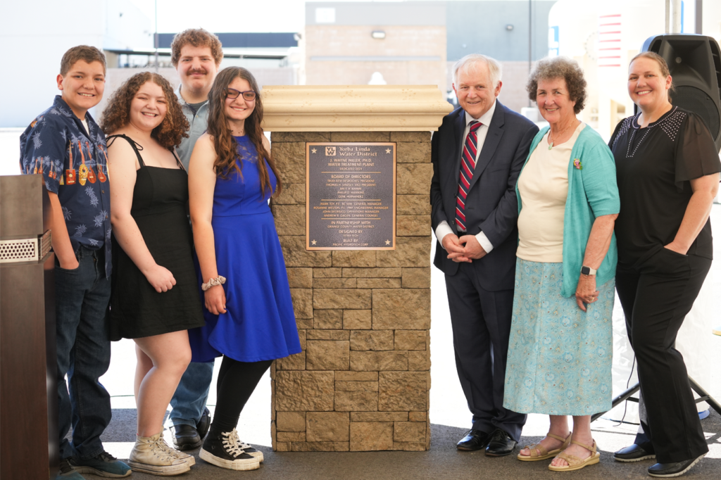 Doctor Miller poses in front of his plaque and podium with his family.