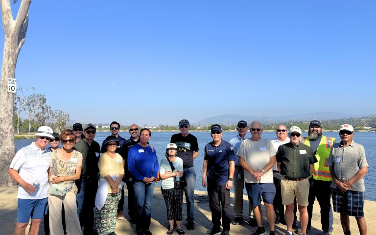 18 people take group photo in front of body of water, featuring YLWD staff and Behind the Bill tour attendees