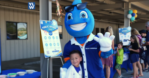 Photo captures a child smiling with a water drop mascot at an event.